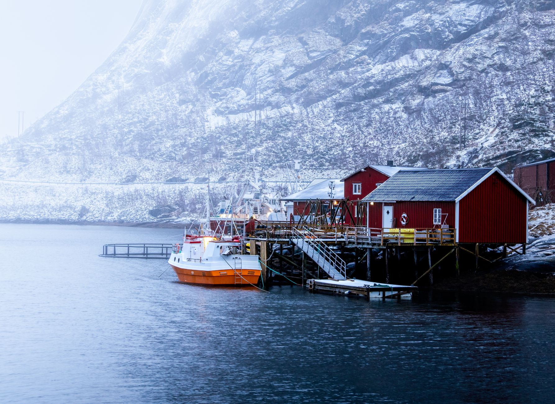 Arctic wooden house by cold fjord with snow